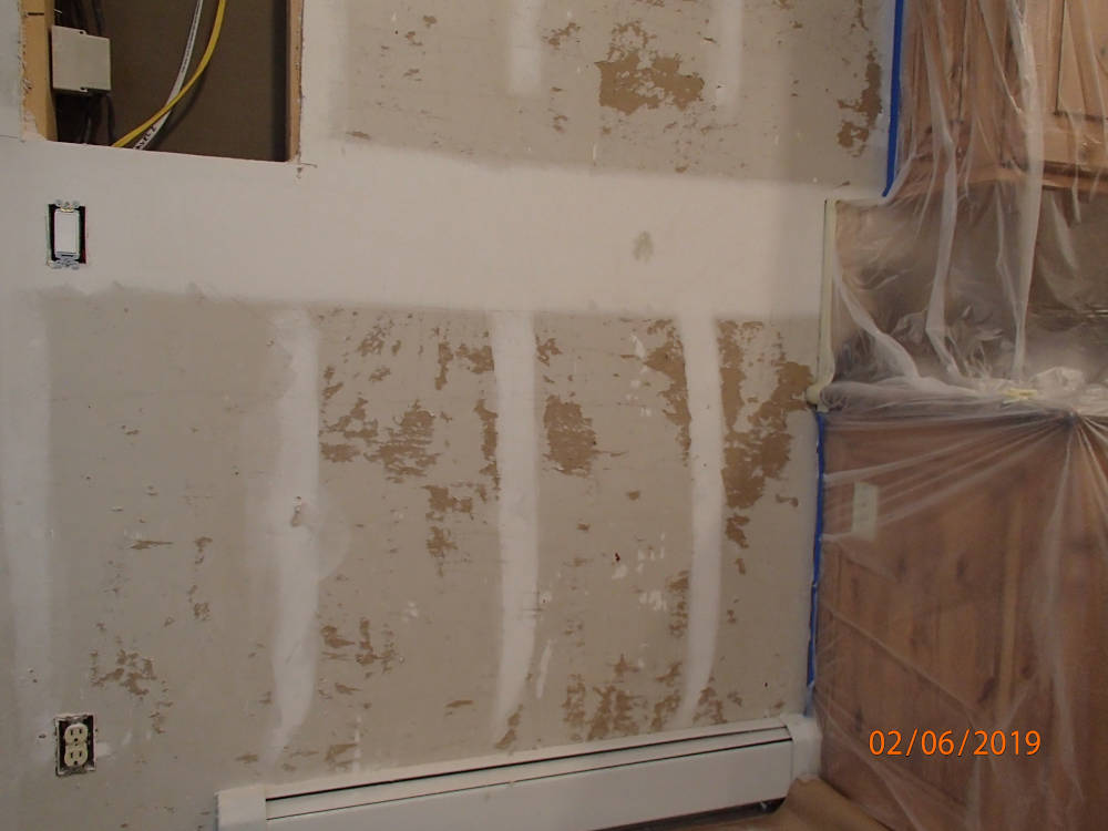 showing a wall where wallpaper was removed and drywall repair is needed.
